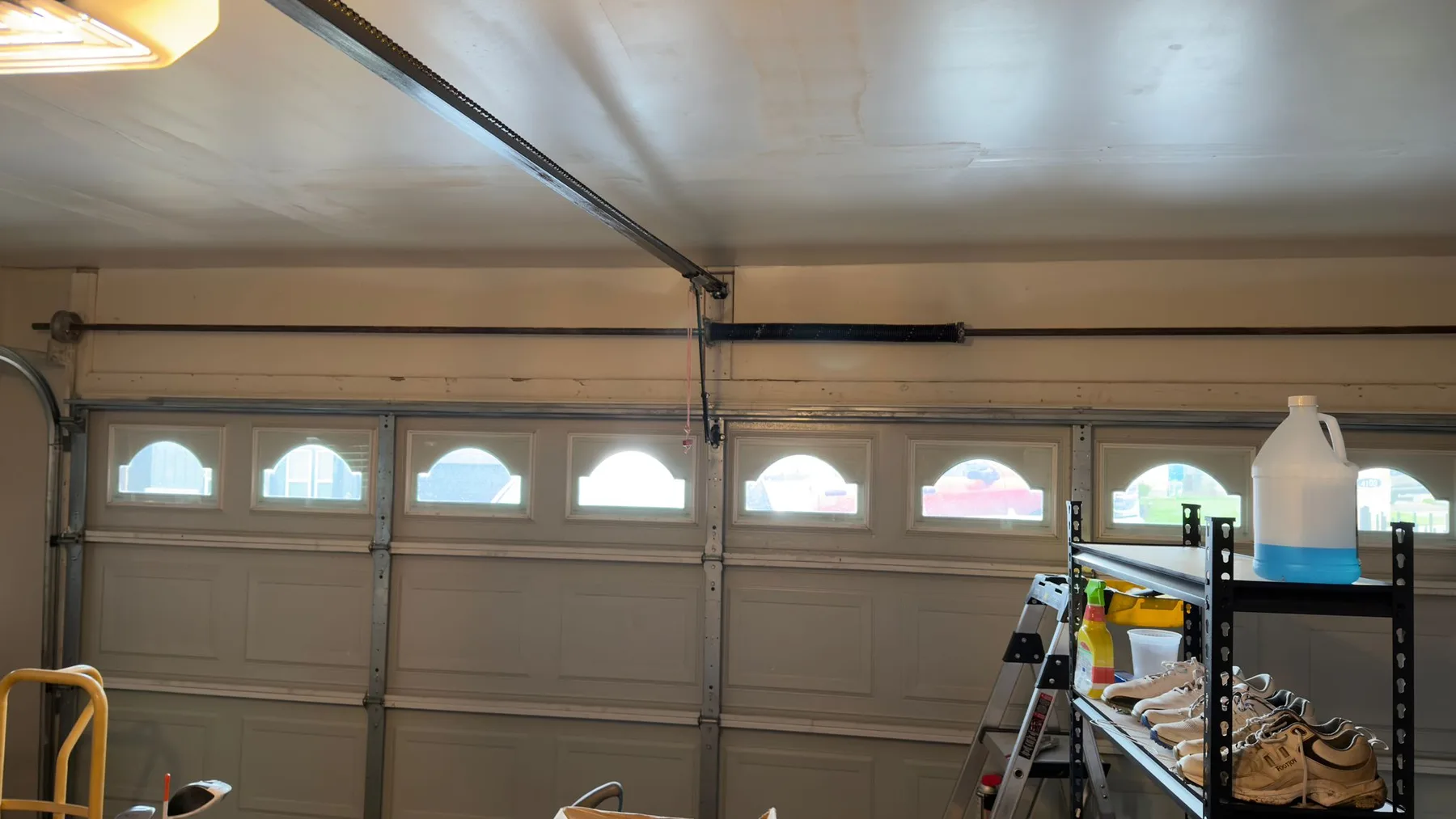 Interior view of a windowed garage door with its torsion shaft and opener rail in Shockwave's Austin-area work gallery.